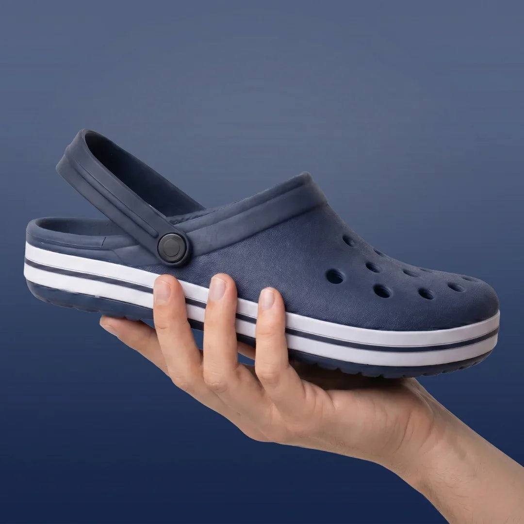 Chinelo azul marinho com sola branca e furos, segurado na mão, ideal para conforto e uso casual.