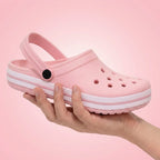 Chinelo rosa com sola branca e furos, segurado na mão, ideal para verão e conforto.